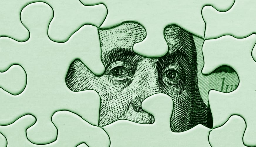 An image of a puzzle with one piece missing and hundred dollar bill revealed.