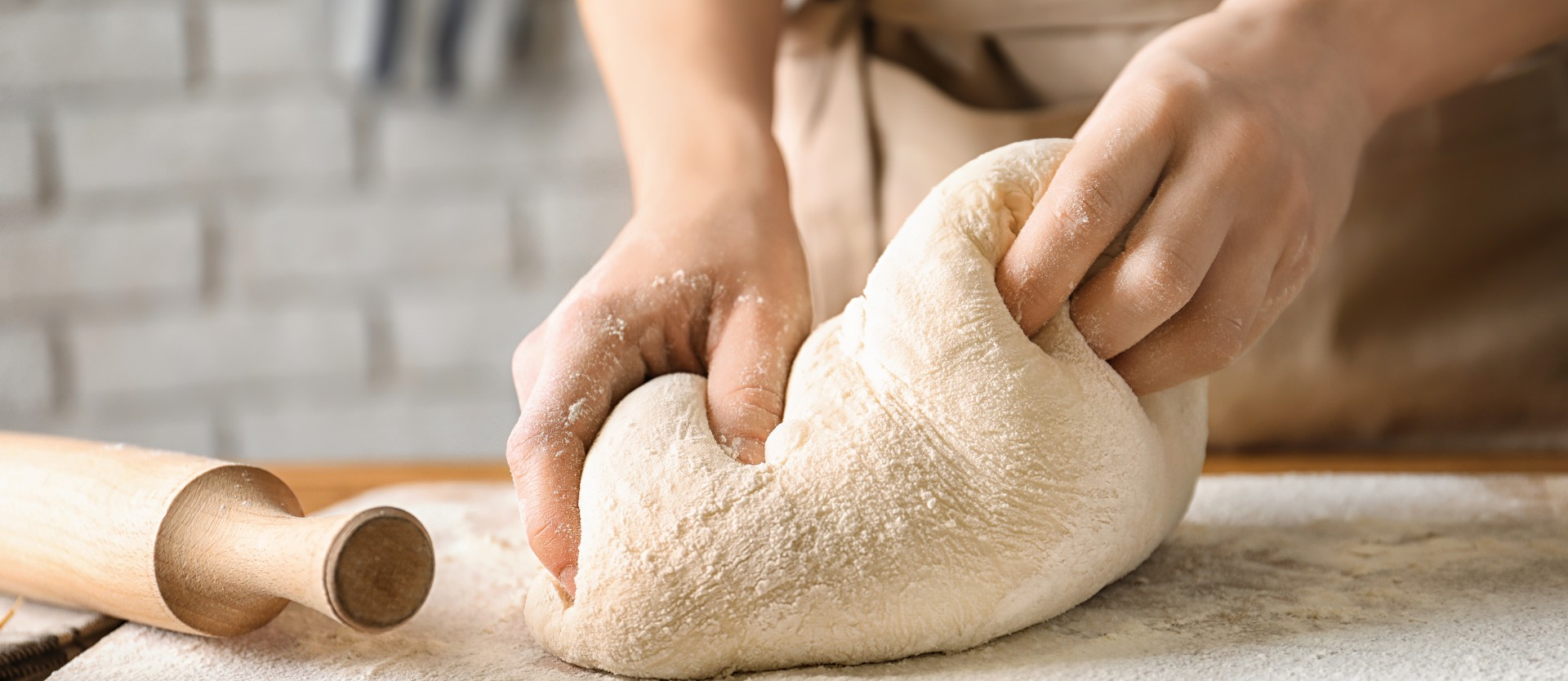 Woman kneading dough on board sprinkled with flour